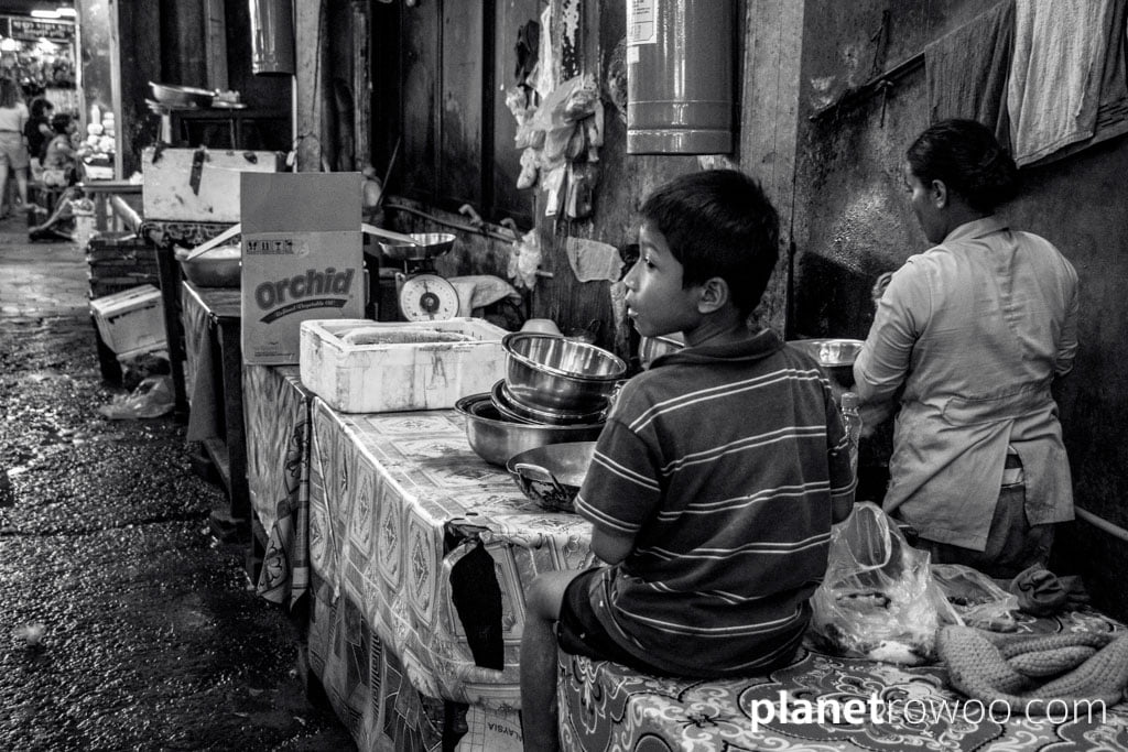 Young boy waits as his mother works at Psar Chaa Old Market, Siem Reap, Cambodia, 2018